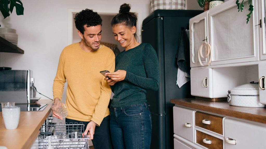 Una pareja mirando el teléfono inteligente en la cocina
